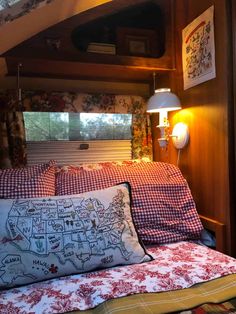 a bed with red and white checkered sheets in a room next to a window