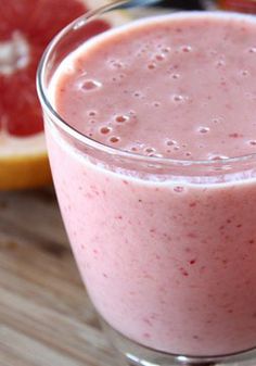 a close up of a drink in a glass on a table with grapefruit