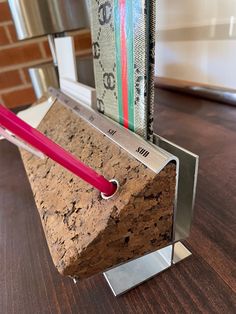 a pen holder made out of cork and metal with a pink toothbrush sticking out of it