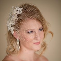 a woman wearing a veil and head piece with pearls on the side is looking at the camera