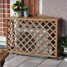 a wooden cabinet sitting on top of a tile floor next to a potted plant