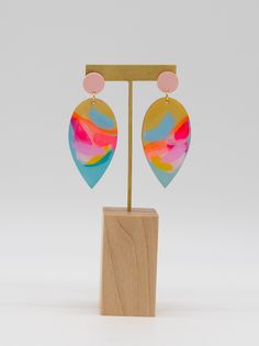 Turn heads, and make hearts flutter with these carefully crafted hand painted earrings. These multi-color beauties shimmer and shine with a resin finish and iridescent details. Plus, the gold accents and gold finished hardware add a luxe touch. Eye-catching and unique, these earrings make a fun statement! Colors will vary on different screens. Most appear brighter in person. Multicolor Resin Earrings For Pierced Ears, Multicolor Resin Earrings, Hand Painted Multicolor Earrings For Party, Hand Painted Multicolor Party Earrings, Artistic Multicolor Resin Earrings, Multicolor Resin Drop Earrings, Hand Painted Pink Resin Earrings, Multicolor Heart-shaped Hand Painted Earrings, Whimsical Hand Painted Gold Earrings