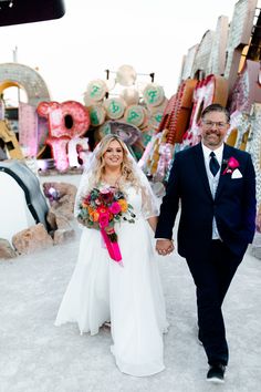 A radiant couple immersed in happiness, featuring a bride in a timeless wedding dress and elegant hairstyle, and a groom in a dapper navy blue suit. Their vibrant bouquet pops against vintage neon signs, capturing unique wedding ideas in a nontraditional setting. 🌸✨ Make your day unforgettable with this inspiration! ❤️ #weddingideas #timelessweddingdress #uniquevibes #neonmuseumwedding #engagementphotos Museum Elopement, Small Private Wedding, Intimate Elopement Ideas, The Neon Museum, Very Small Wedding