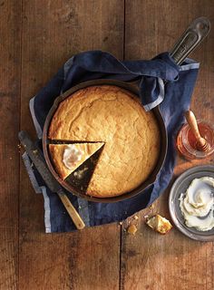 a pie sitting on top of a wooden table next to a knife and some butter