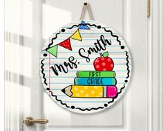 a door hanger that says, mrs smith first grade with an apple on top of books