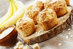 some muffins are sitting on a wooden board next to bananas and oatmeal