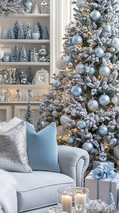 a living room decorated for christmas with silver and blue decorations on the tree, white couches and coffee table