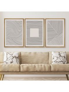 three framed art pieces hanging on the wall above a beige couch with pillows and throw pillows