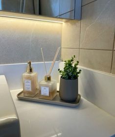 a bathroom sink with two candles and a potted plant