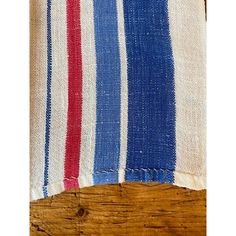 a red, white and blue striped towel on top of a wooden table next to a piece of wood