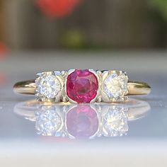 Details: Lovely Mid Century 14K yellow and white gold diamond and ruby ring, with two diamonds and a ruby. The ruby has a lovely rich pink color, and measures approx. 4.43mm. The two diamonds measure approx. 3.75mm. The diamonds and ruby are set in white gold, while the band is yellow gold. The interior of the ring has a sweet heart hallmark that says 14K. Please ask all necessary questions prior to placing an order. Measurements: The size is 6 3/4 US and can be sized for a fee. Condition: The o 2stone Ruby Ring, Red Diamond Ring With Rose Cut Lab-created Ruby, Classic Red Three Stone Diamond Ring, Classic Three Stone Ruby Ring With Diamonds, Classic Three-stone Ruby Ring, Red Three-stone Ruby Ring, Classic Three Stone Ruby Ring, Red Diamond Ring With Single Cut Diamonds, Red Ruby Three Stone Round Cut Ring