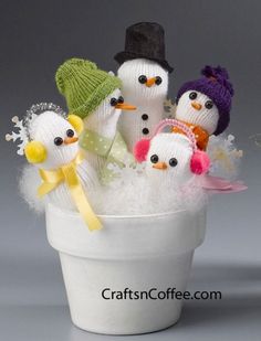 a group of knitted snowmen in a white cup filled with water and snow