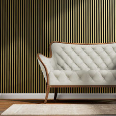 a white couch sitting on top of a wooden floor next to a black and gold wall