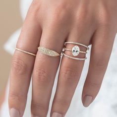 a woman's hand with three rings on her fingers and one ring in the middle