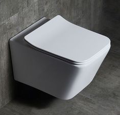 a white toilet sitting on the side of a wall next to a gray tiled floor