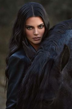 a woman with long black hair is standing next to a horse