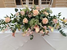 an arrangement of flowers on a white table cloth