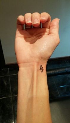 a woman's wrist with a small tattoo on the left side of her arm