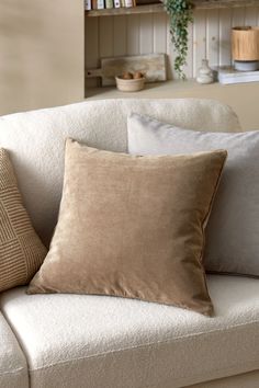 a couch with two pillows on it and a book shelf in the backround