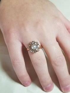 a woman's hand with a pearl and diamond ring on top of her finger