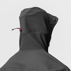 a person wearing a black jacket with a red button on the back and hood up