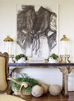 a table with two vases and some plants on it in front of a painting