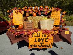 a table that has some signs on it with pumpkins and hay in the background