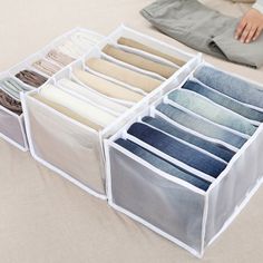 a person sitting on the floor next to an open drawer filled with folded shirts and pants