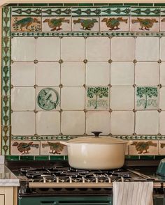 a stove top oven sitting inside of a kitchen next to a green and white tile backsplash