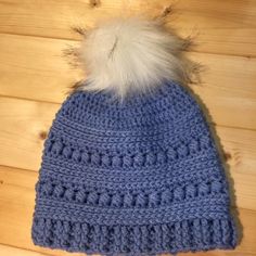 a blue knitted hat with a white pom - pom