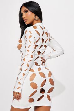 a woman wearing a white dress with brown spots on the back and long sleeves,