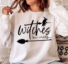 a woman sitting on a couch wearing a white shirt with witches be crazy written on it