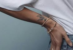 a person with a tattoo on their arm wearing jeans and a white t - shirt