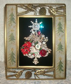 a christmas tree made out of flowers and pine cones is framed in a gold frame