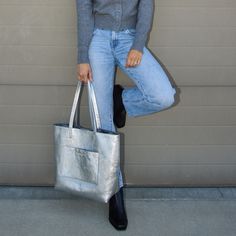 This exquisite Silver Everyday Tote is carefully crafted from luxuriously textured silver leather, accompanied with two shoulder straps. This timeless piece features a charcoal gray antigoccia coating interior lining and two interior zipper pocket for extra security, with an additional exterior zipper pocket. This everyday tote bag fits a 14" laptop, this handbag is crafted with Italian finesse and is the perfect summer accessory. Style Quizzes, Nickel And Suede, Everyday Tote Bag, City Woman, Luxe Jewelry, Everyday Tote, Everyday Accessories, Summer Accessories, Metallic Leather