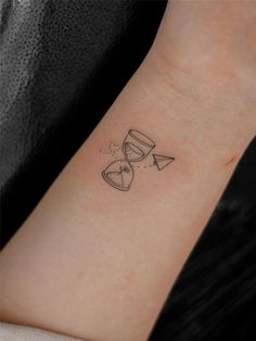 a woman's wrist with an hour and hourglass tattoo on it