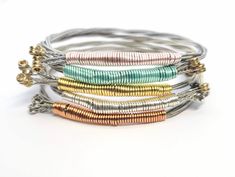 This music inspired bangle bracelet is custom made with recycled guitar strings in your size and favorite color! These are truly unique pieces of handmade jewelry that make the perfect gift for music lovers, guitar players, musicians, concertgoers and the rockstars in your life! ⚡ D E T A I L S ⚡ ✦ Guitar string bracelet wrapped in wire - choose your favorite color from 13 options! ✦ Size: Made-to-order in sizes XS-XXL. (This is a bangle bracelet and slides over the hand. Please measure the widest part of your hand around the knuckles.) XS - 7" S - 7.5" M - 7.75" L - 8 XL - 8.25" XXL - 8.75" ✦ Guitar string is flexible, but does not stretch or adjust in size. If it's not a good fit, no worries! You can exchange it for a different size within 14 days. ✦ Free Shipping: Your order ships fast Guitar Bracelet, Guitar String Jewelry, Guitar String Bracelet, Beaded Jewelry Bracelets, Guitar Pics, Guitar Players, Music Jewelry, Festival Jewelry, Eco Friendly Jewelry