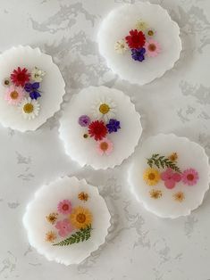 four plates with flowers on them sitting on a table