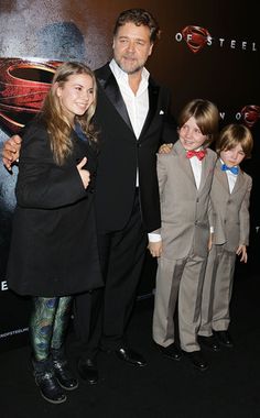 a man and two children standing next to each other in front of a superman movie poster