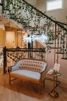 a couch sitting under a neon sign next to a stair case