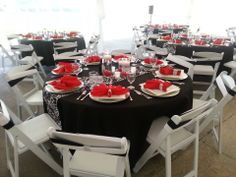 the tables are set with black and white linens, red napkins, and silverware