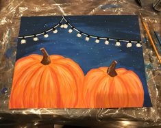 an acrylic painting of two pumpkins with string lights on the top and bottom