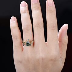 a woman's hand with a ring on top of it and an emerald stone in the middle