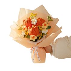 a person holding a bouquet of flowers with oranges and yellows in it's hands