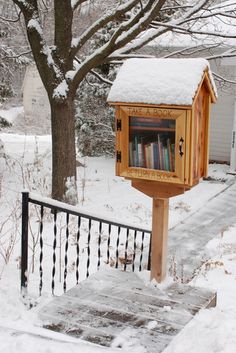 the mailbox is covered in snow and there are books on it's shelf