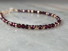 This gorgeous bracelet is made with vivid scarlet red faceted round Garnet and highly polished 14k Yellow Gold filled beads. The deep red gemstones are perfectly complimented by the warm yellow of 14k gold, and combined, come together to become a stunning piece of art, and jewelry.        ∆  M A T E R I A L S  ∆ * 3.5mm Faceted Round Red Garnet * 14k Gold Filled Hardware and Spring Ring Clasp ( 14k Gold Filled Lobster Claw Clasp Available as Add On) * Your Choice of Gold Filled Spacers:  ---2mm(Small) Round Beads ---2.5mm(Medium) Round Beads ---3mm(Large) Round Beads ---3mm Rondelles      ∆  14K  G O L D - F I L L E D  ∆ Thirty-Two Karits exclusively hand-crafts our items by using gold-filled materials, high-quality genuine gemstones, and the highest professional grade beading wire with th Red Rondelle Gemstone Beads Bracelets, Faceted Garnet Round Bead Jewelry, Red Faceted Rondelle Jewelry, Red Faceted Round Bead Bracelets, Red Faceted Round Bracelets, Elegant Red Faceted Beaded Bracelets, Red Faceted Elegant Bracelets, Elegant Red Faceted Bracelets, Garnet And Gold