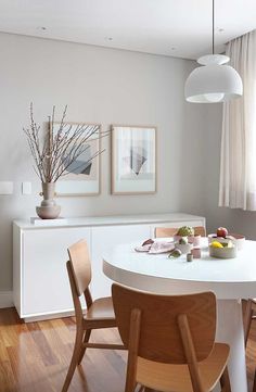 a white dining room table and chairs with artwork on the wall behind it in front of a window