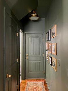 the hallway is painted green and has pictures on the wall above the door, along with a rug