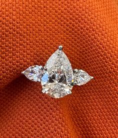 an orange sweater with three pear shaped diamonds on it