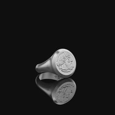 a silver ring with a coin on the side and reflection in the dark background,